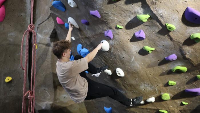 student climbing rock wall
