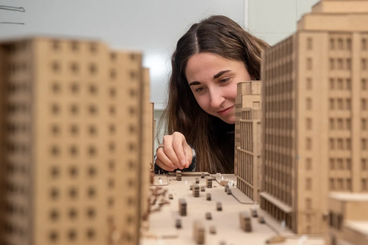 Architecture student working on model of city.
