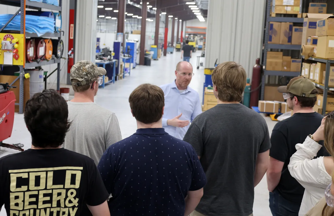students listen while taking a tour of a factory