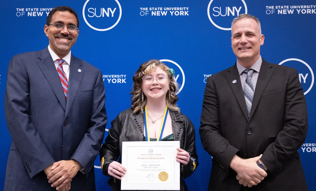 student poses with President and Chancellor after winning an award