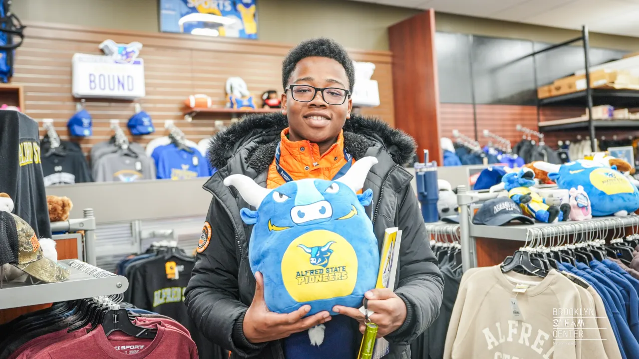 A Brooklyn STEAM student checks out merchandise at the Alfred State Bookstore
