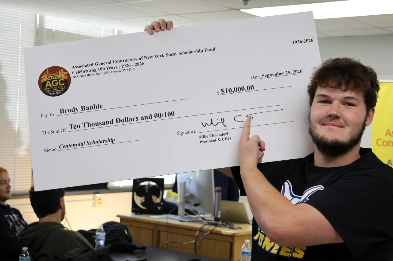 student poses with a scholarship check