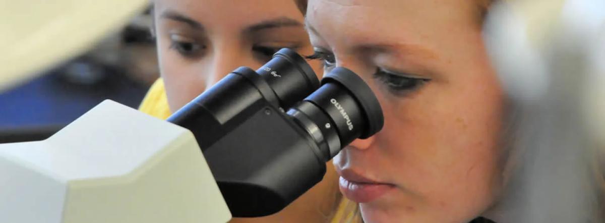 Student looking through microscope.