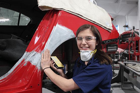 student with a mask near a red car