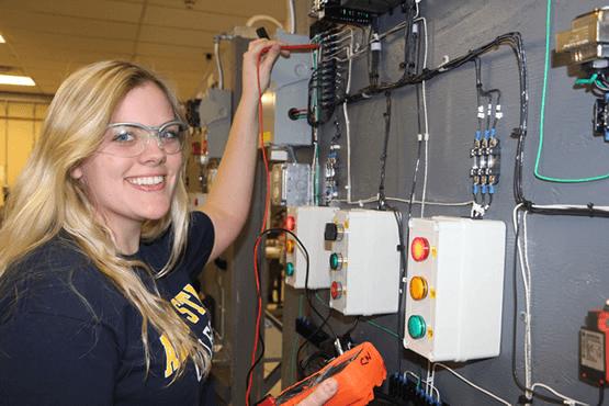 Claire Wragg holding a tool near some wires on the wall