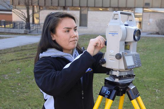 female student with survey equipment outside