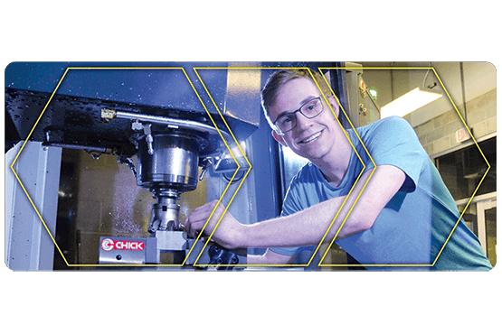 Student leaning into CNC Machine with safety glasses