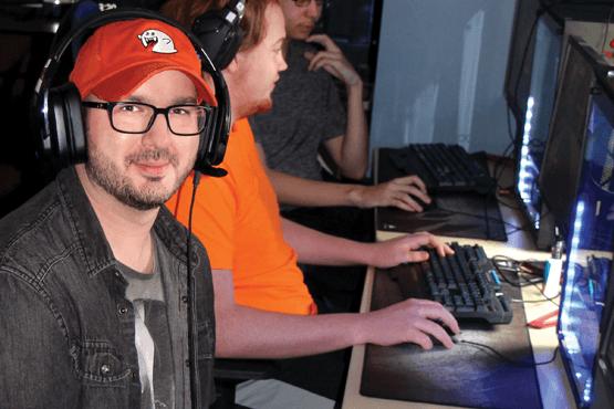 Eric Doty sitting in front of computer with headphones on wearing red hat