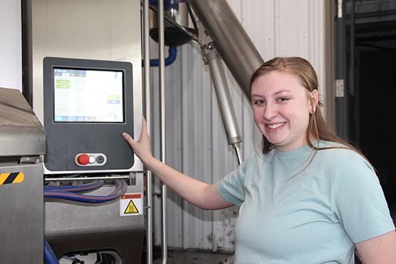 Katelyn Miller works on the robotic milking system at the barn
