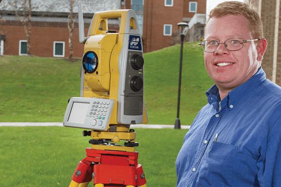 Roger O’Toole next to surveying equipment