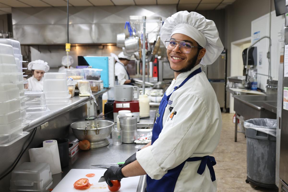 students cuts a vegetable in the kitchen