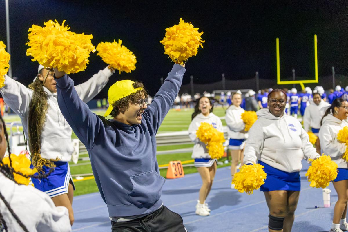 student joins the cheerleaders to keep the crowd excited during Homecoming