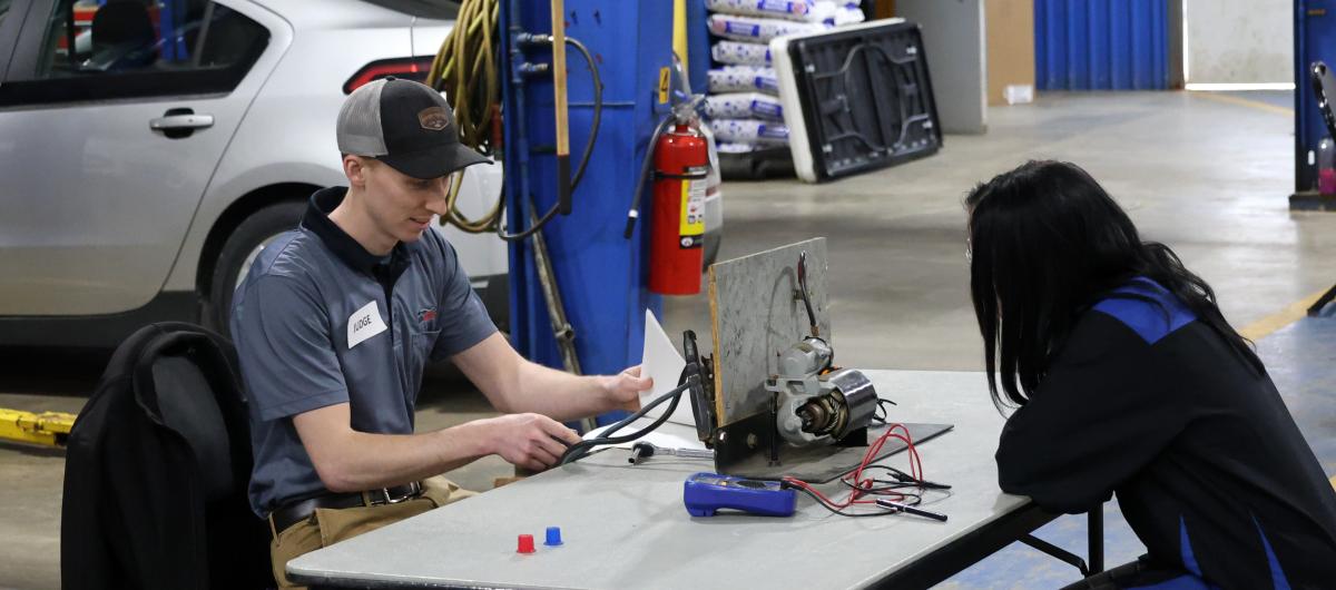 alumnus speaks with a current student at a competition.