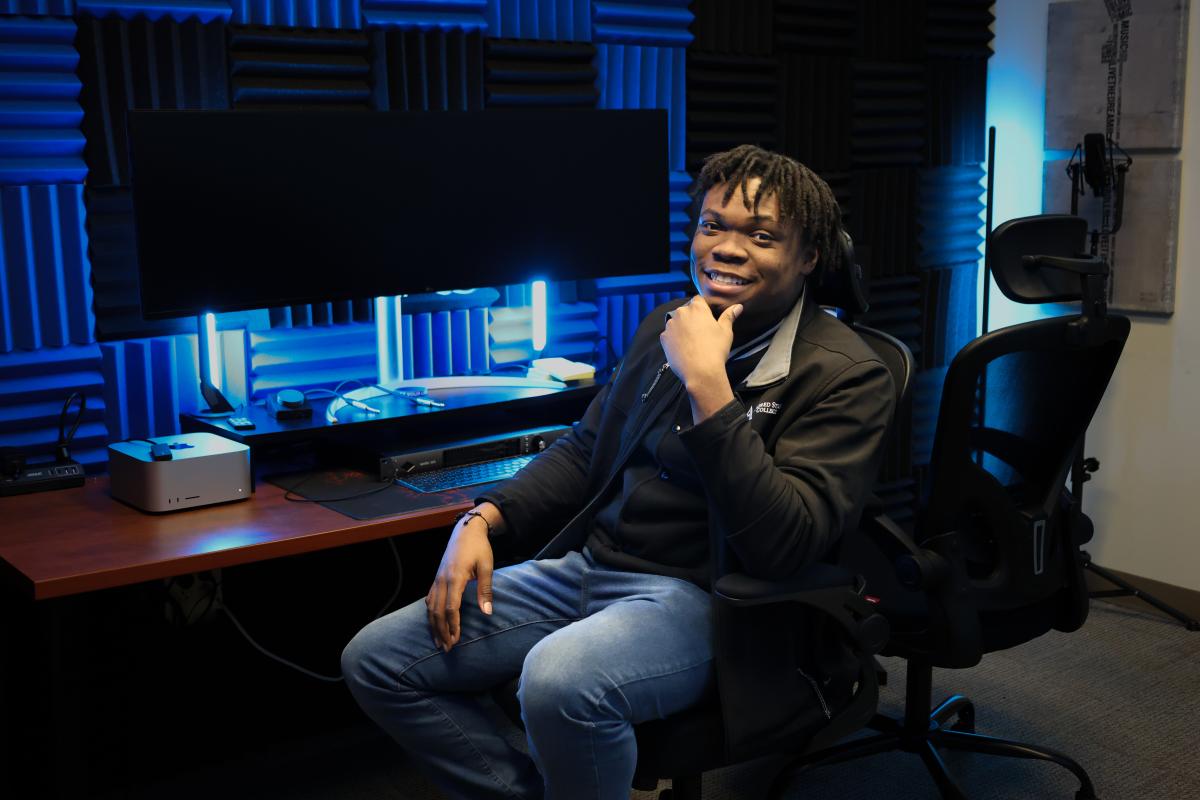 student smiles while sitting in a recording studio