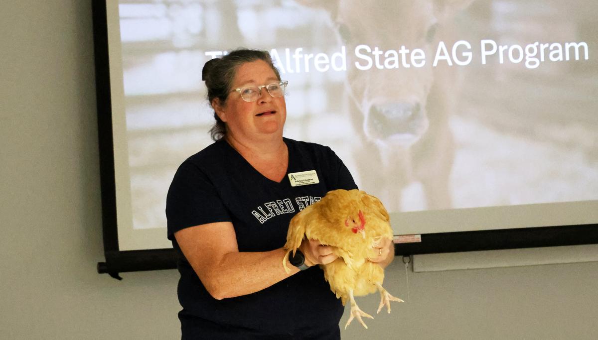 professor holds a chicken while speaking about careers in agriculture