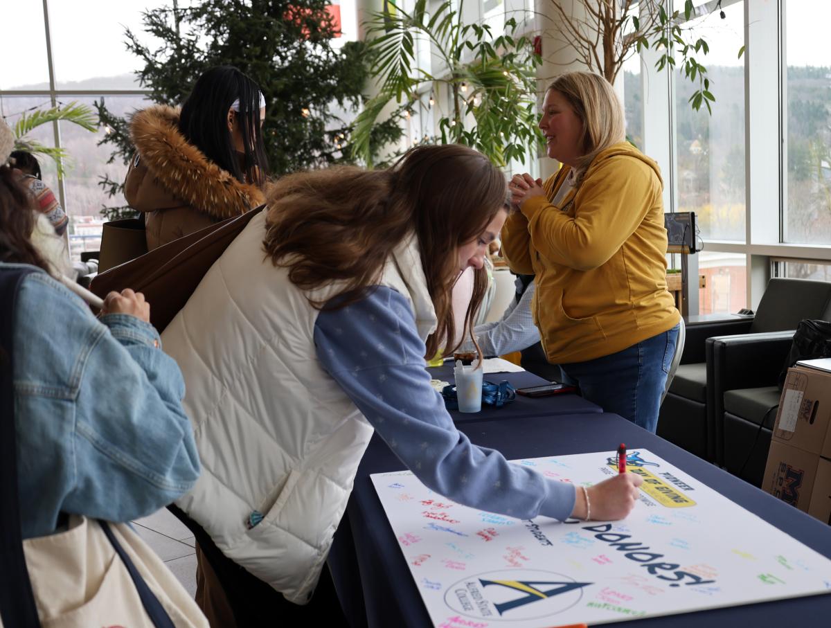 student signs a thank you card