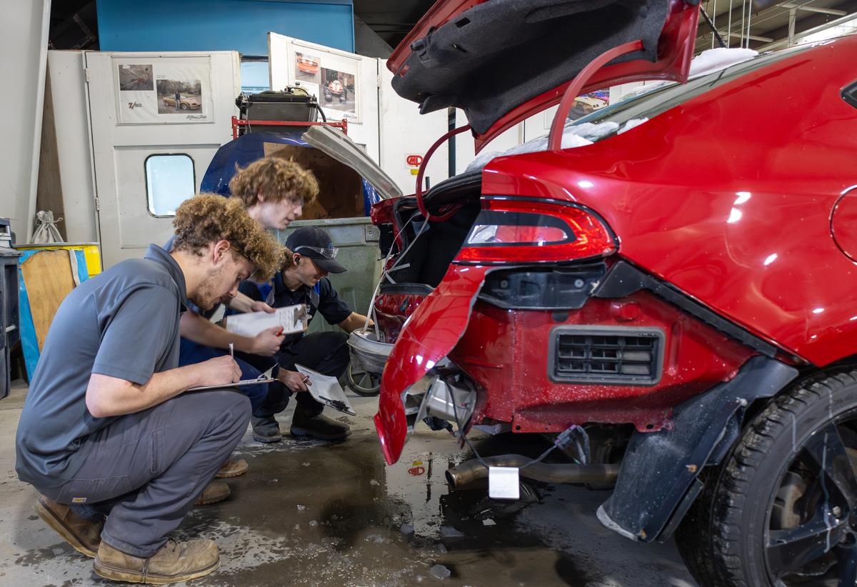 students asses the damage of a car