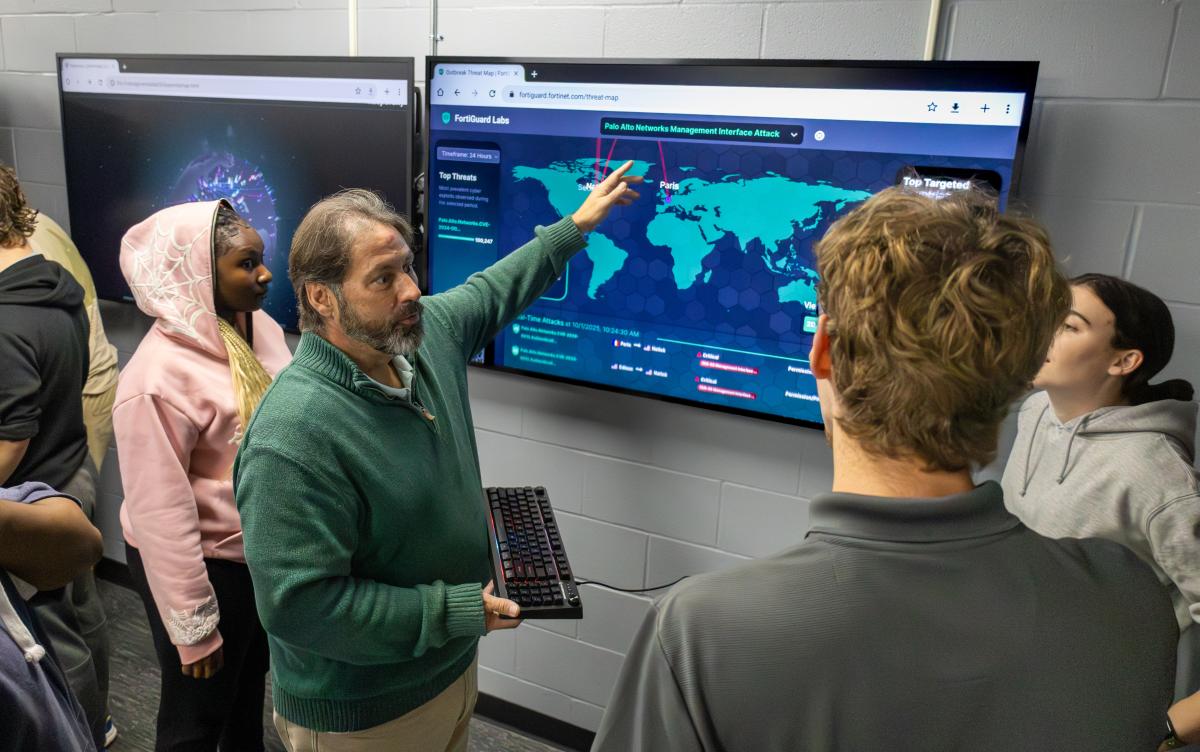 faculty works with students in a cyber security lab