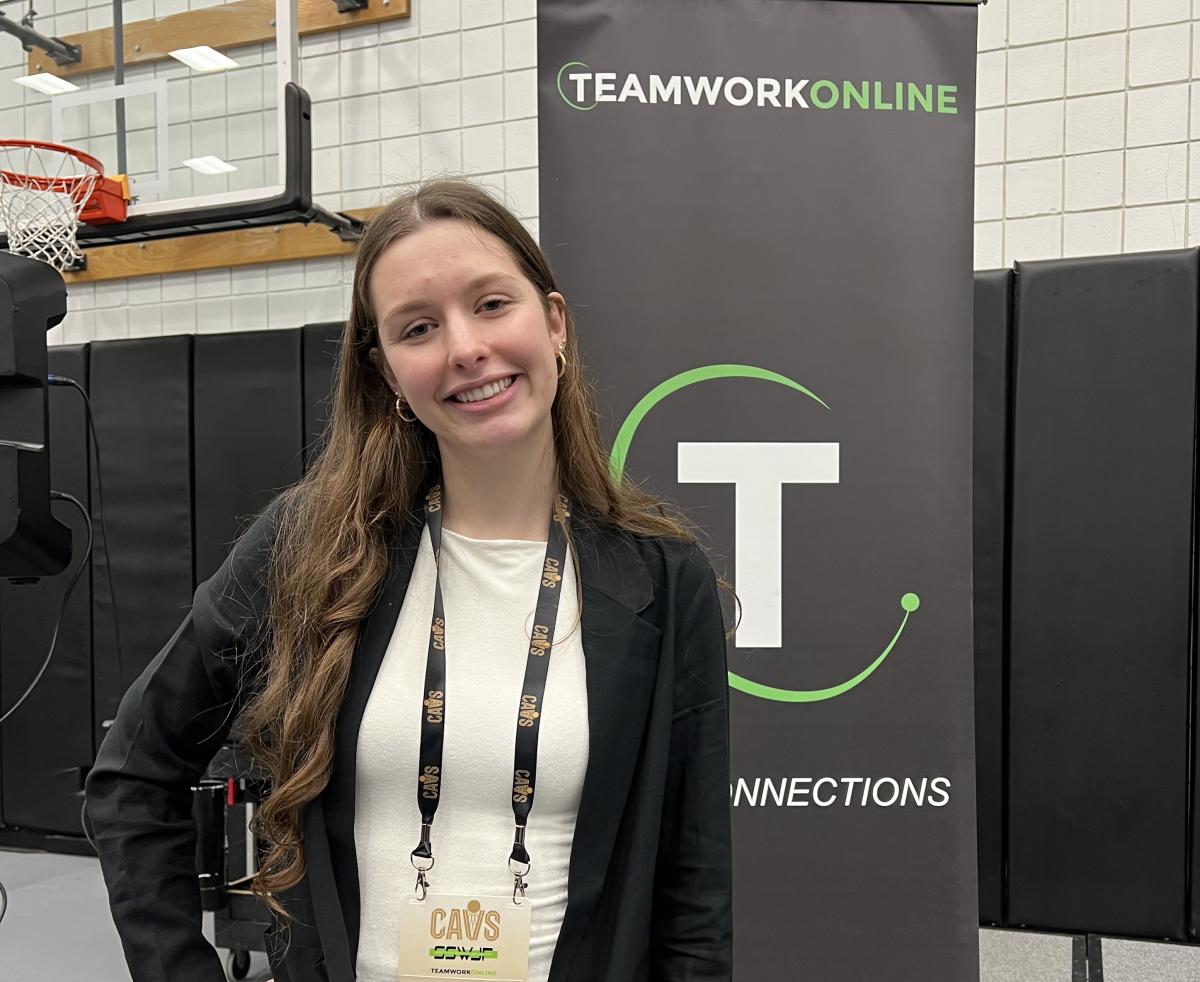 Student posing near a sign at an event with the Cleveland Cavaliers