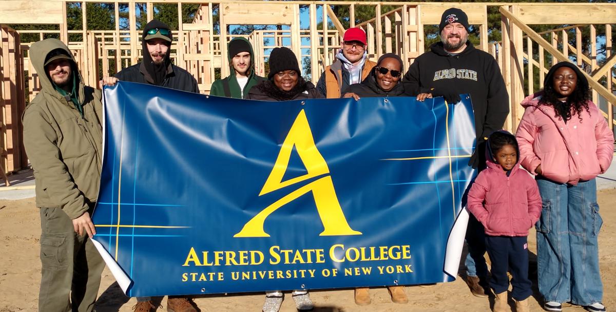 Students stand with a family that they help build a home for