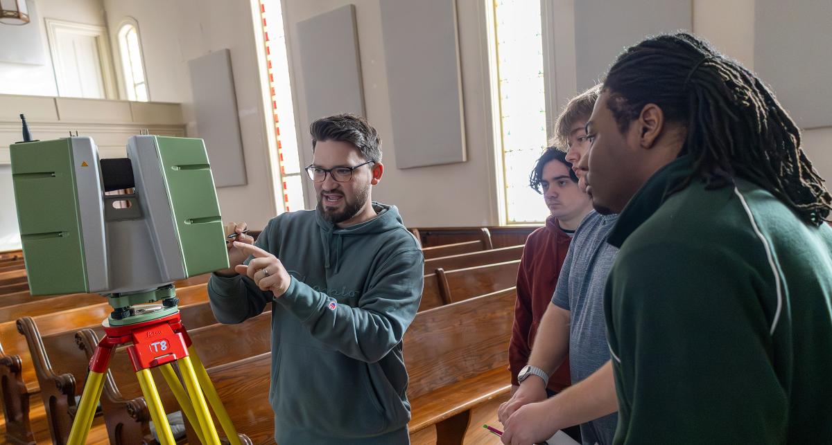 Professor works with students showing them how to use a scanner
