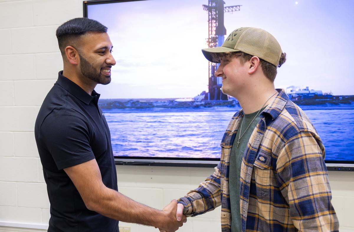 Khobir Uddin shakes hands with a current student