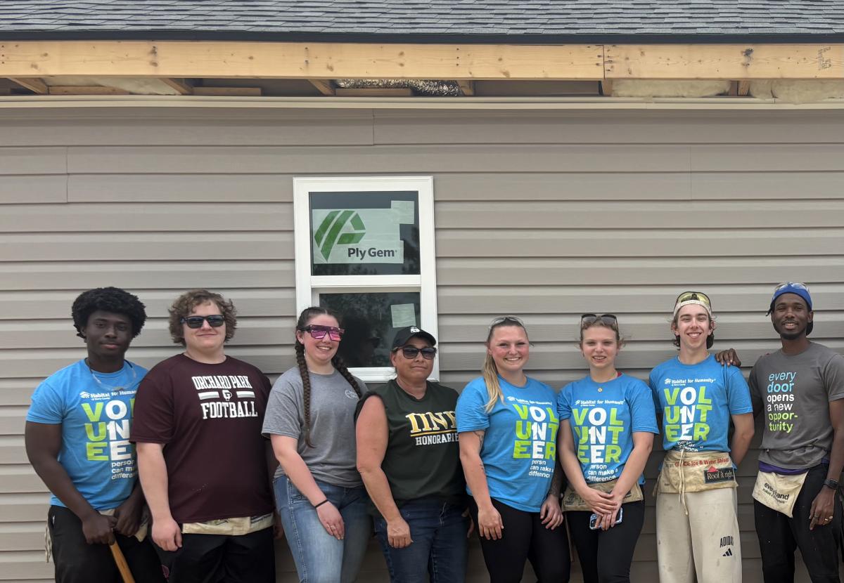 students stand in front of a house they worked on