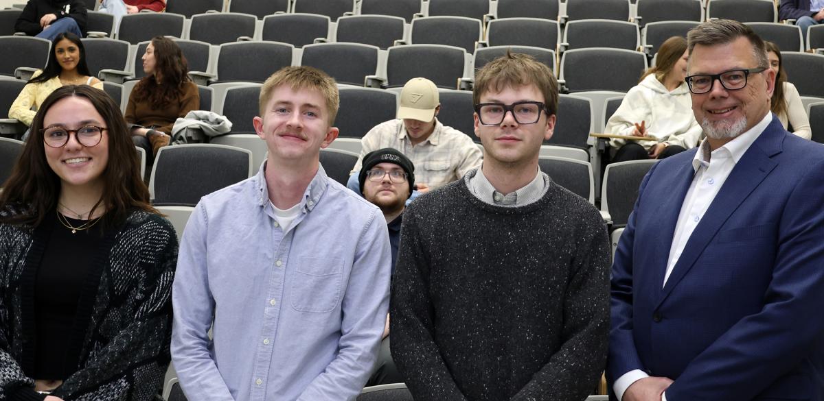 Students stand with their professor after receiving an award