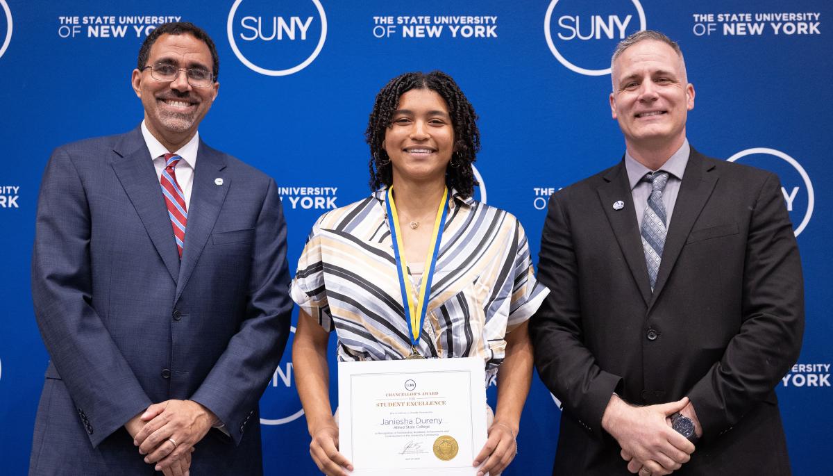 student poses with President and Chancellor after winning an award
