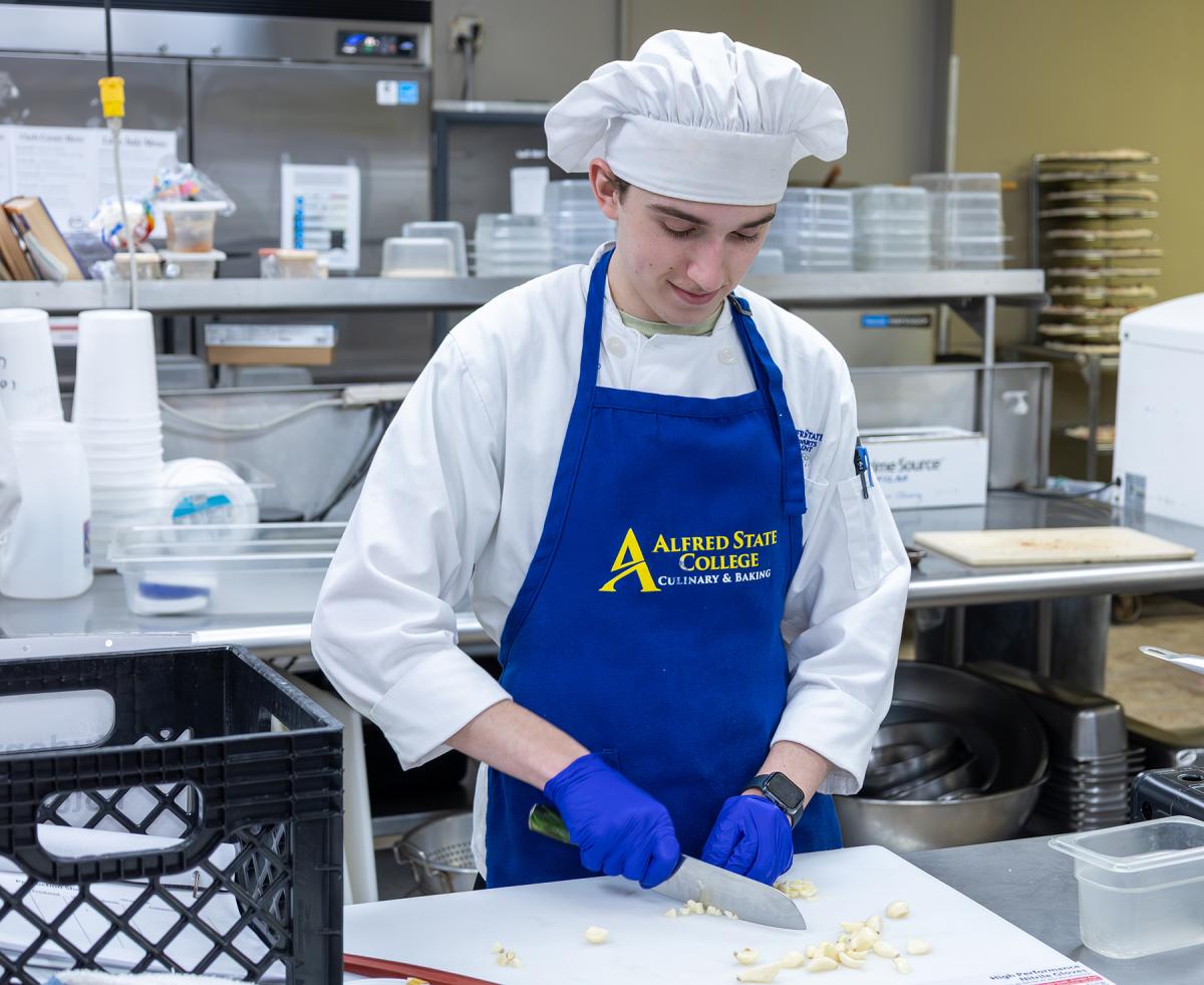 student cuts garlic in the kitchen