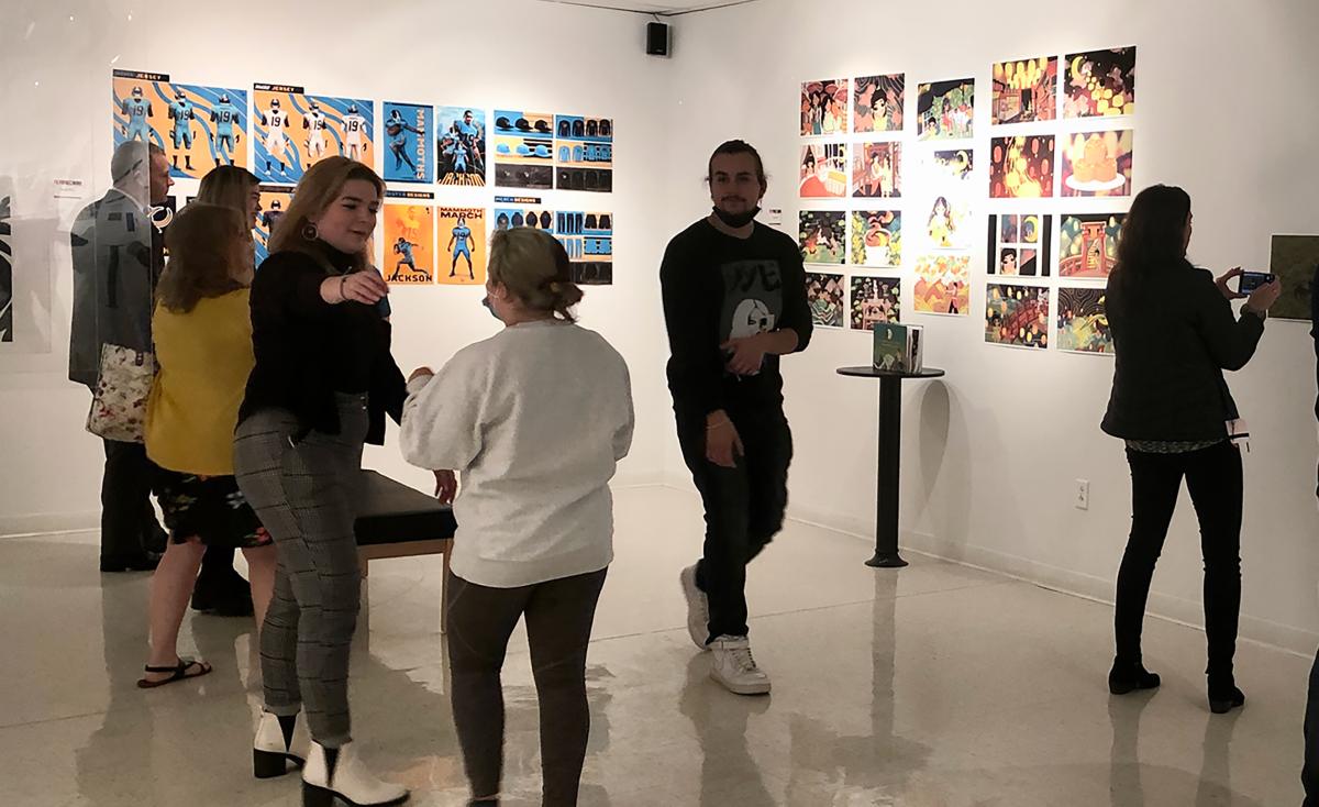 Viewers walking in an art gallery with graphic design work on the walls.