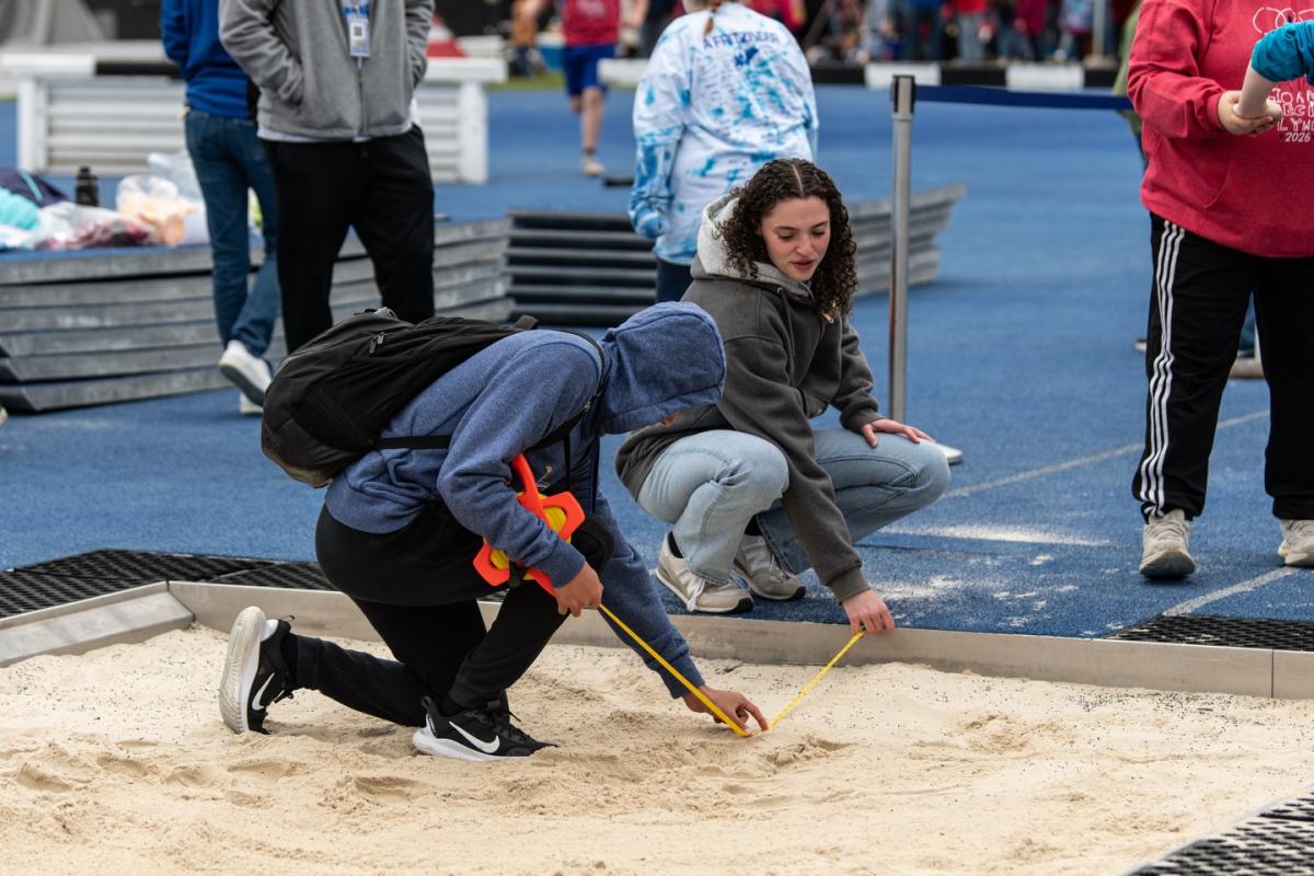 Alfred State student-athletes measure a mark for an athlete participating in a jumping event at the 2026 Alfred State Track & Field Spectacular.