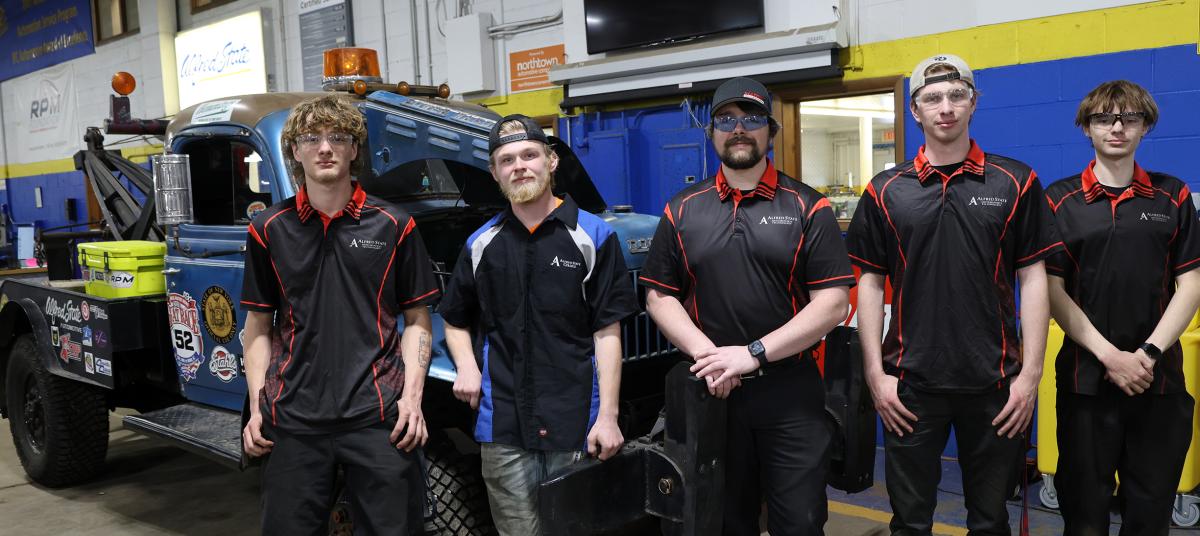 students participating in the Great Race stand in front of their tow truck
