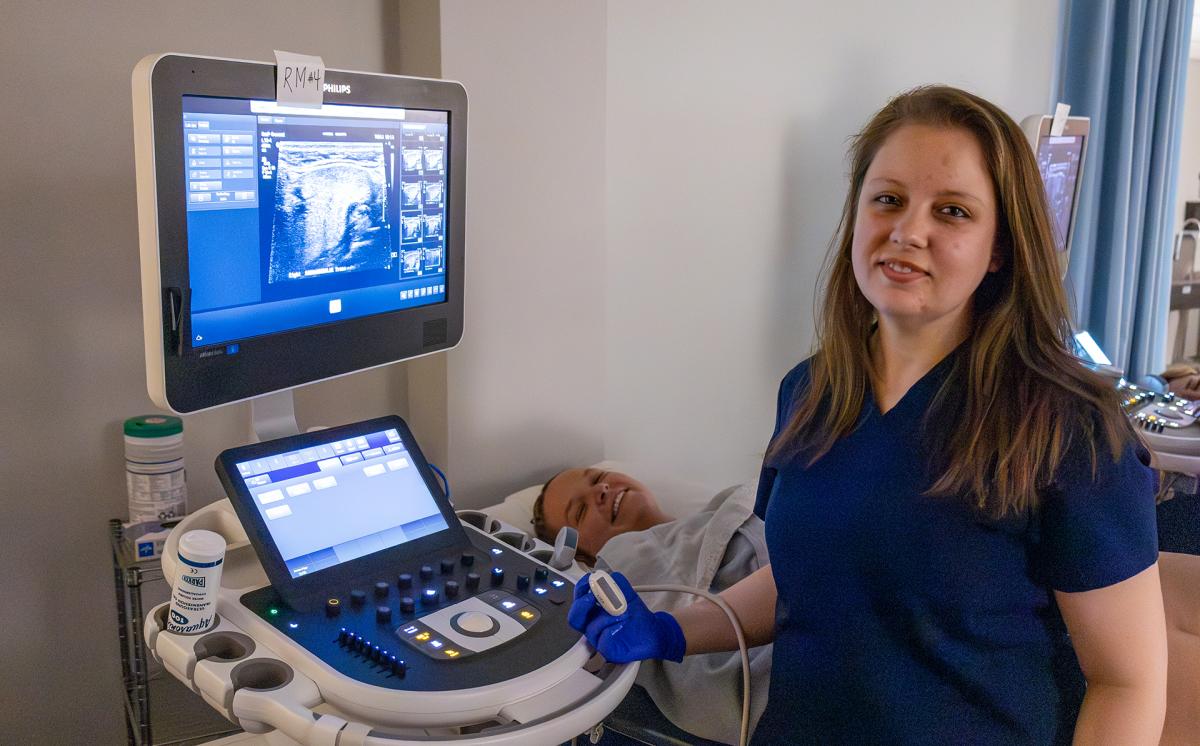 student smiles while working on a sonography machine