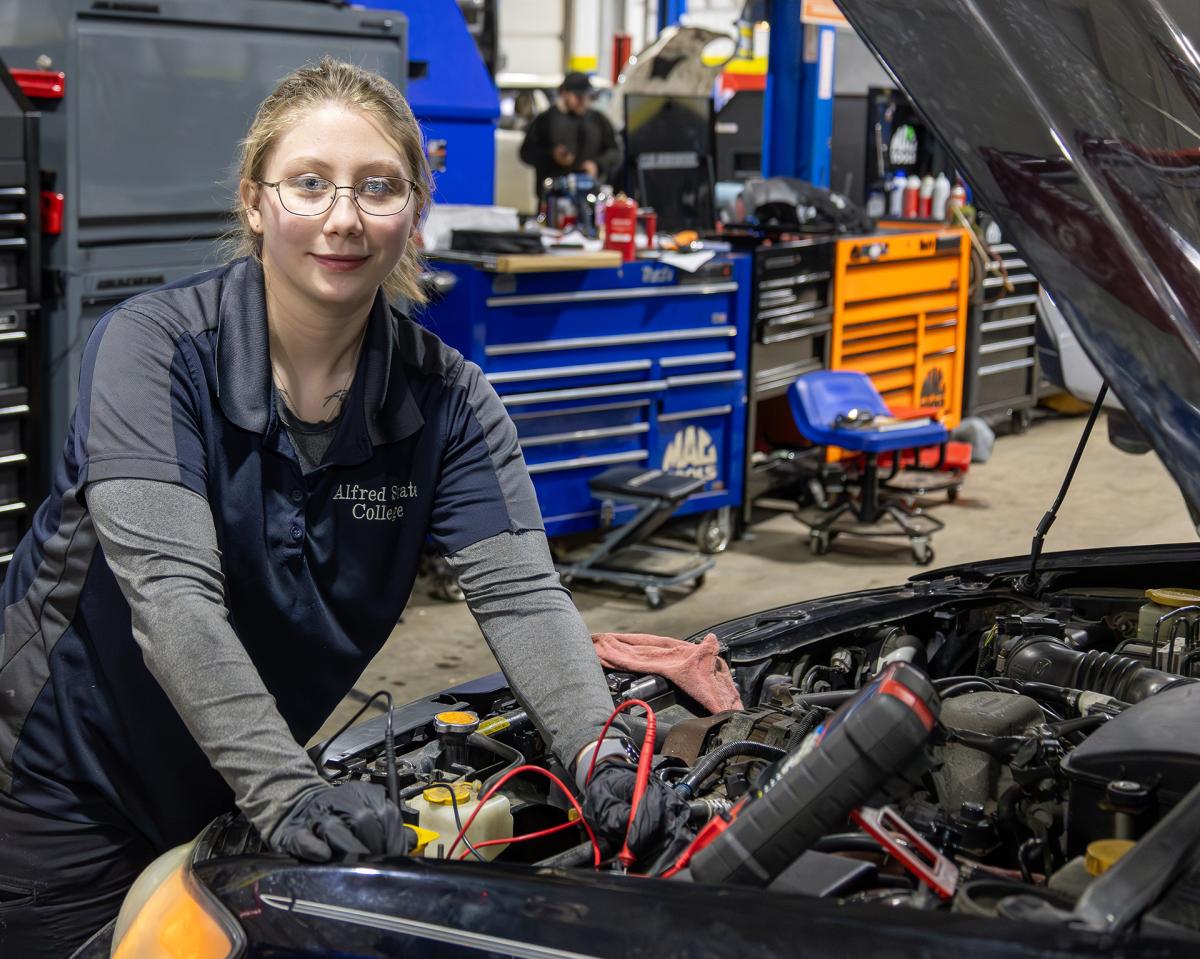 student works under the hood of a car in a shop