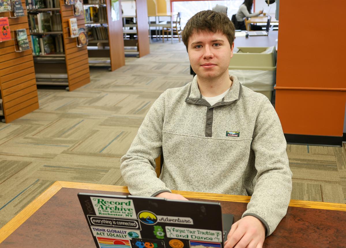 Student sits with laptop in library