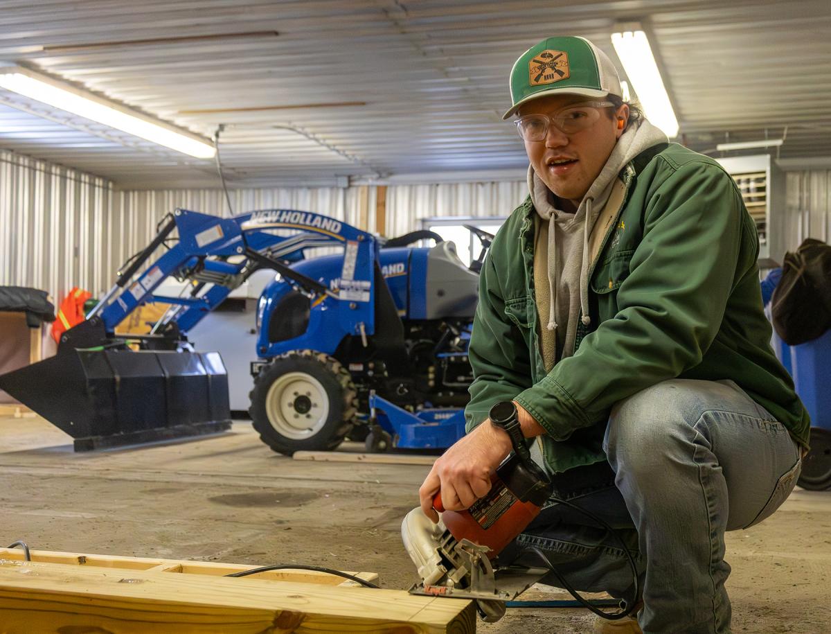 student working on a structure in a barn