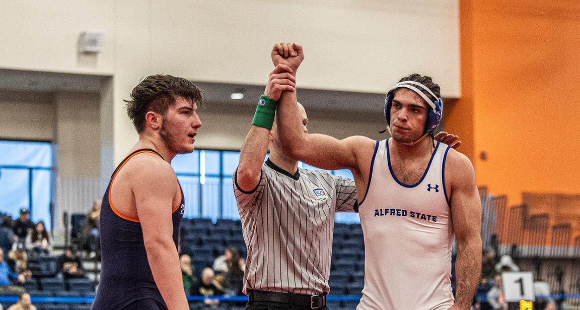 A wrestler has his arm raised in victory