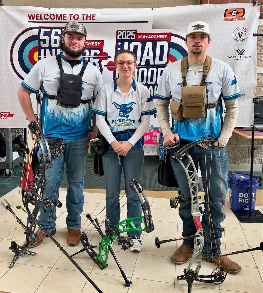 Archers stand in front of a sign at Indoor Nationals