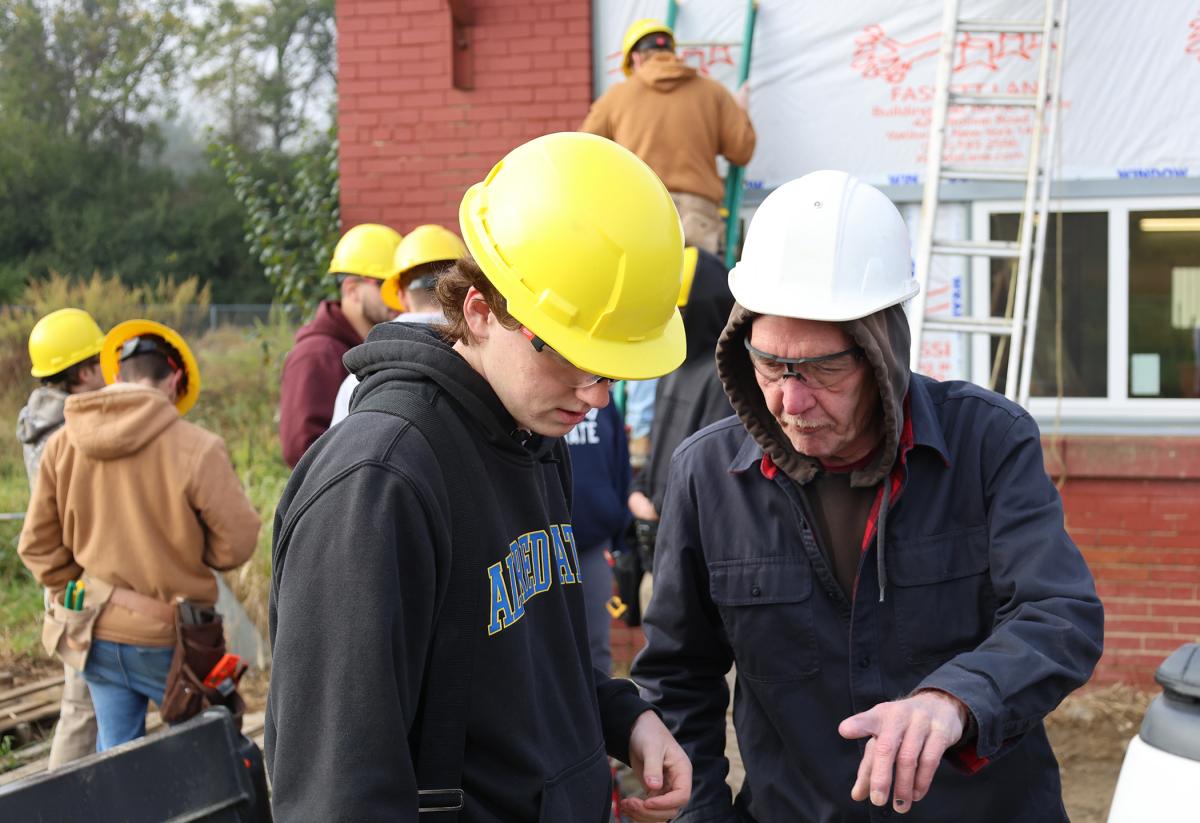 student works with an instructor at a job site