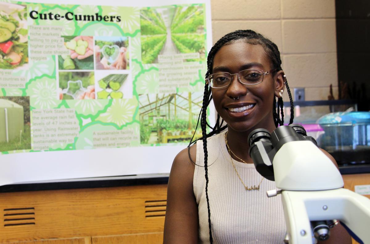 Student sitting next to a microscope