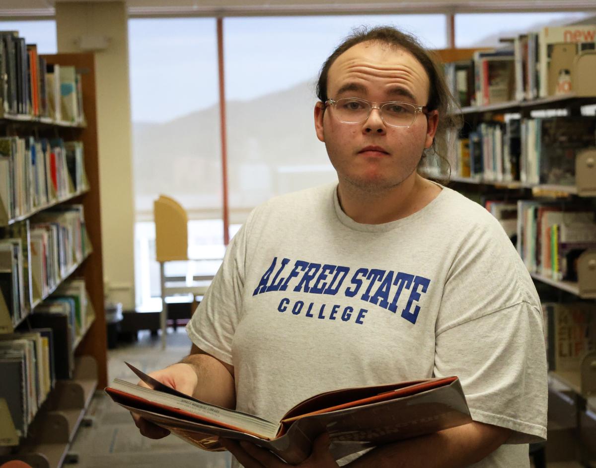 student looking at a book int he library