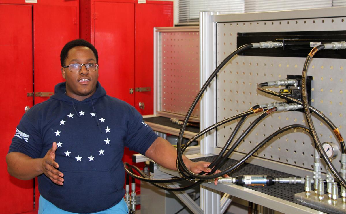 Student standing next to engineering machinery