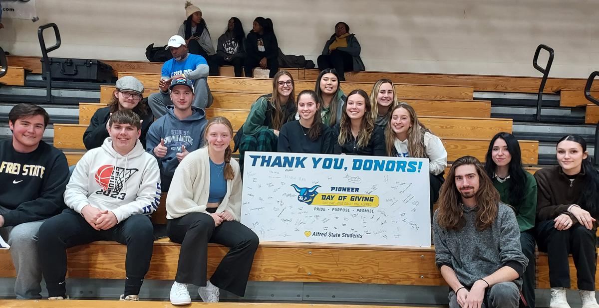 students sitting in the bleachers with a thank you banner.