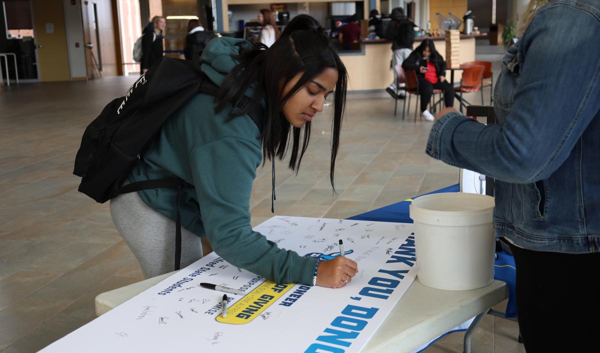 student signs a thank you card