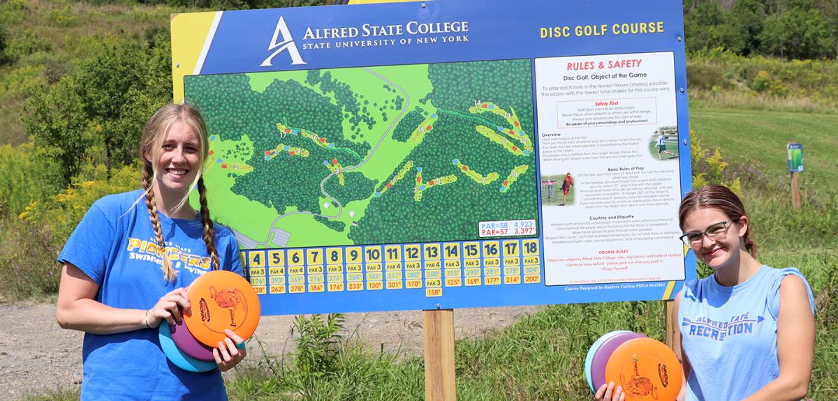 students in front of disc golf sign