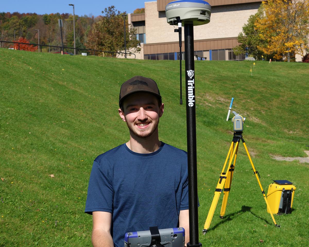 Adam Estes stands with surveying equipment