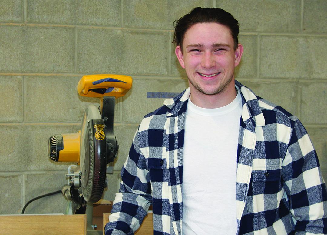Thad Grierson stands in front of a saw in a building trades lab.