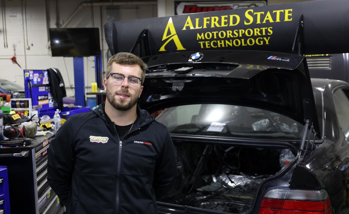 Student stands near sports car