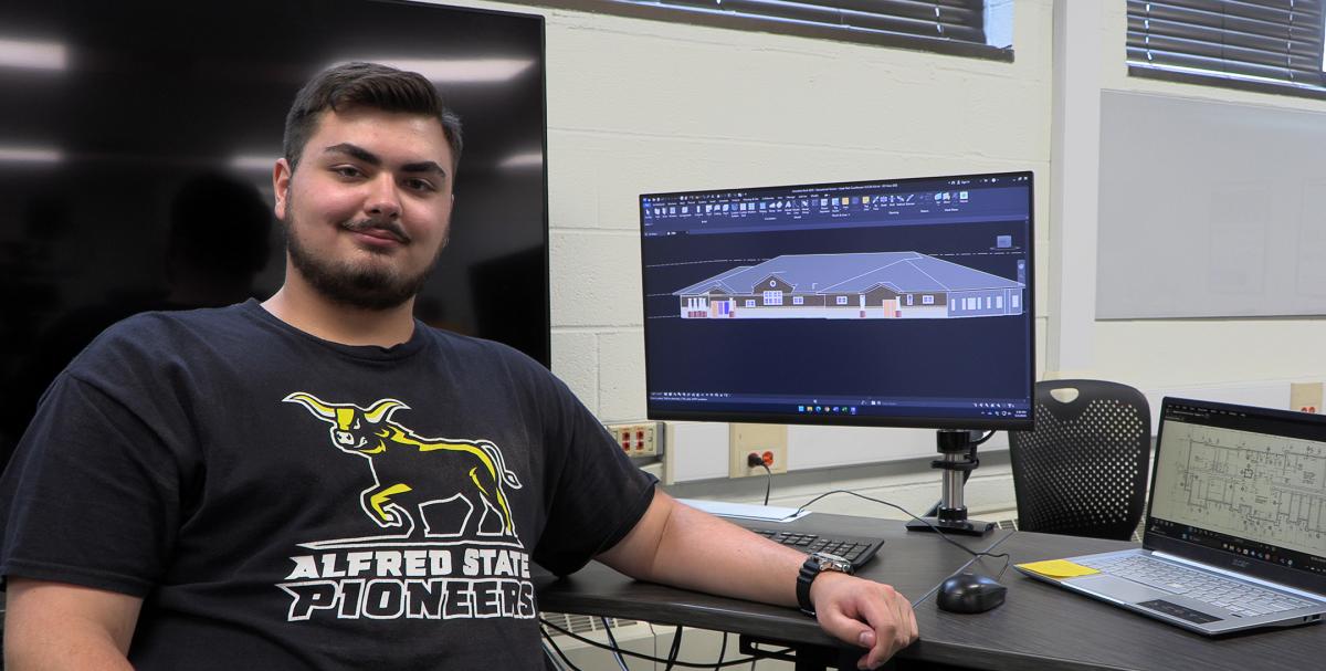 student poses in a lab with a computer screen displays a drawing